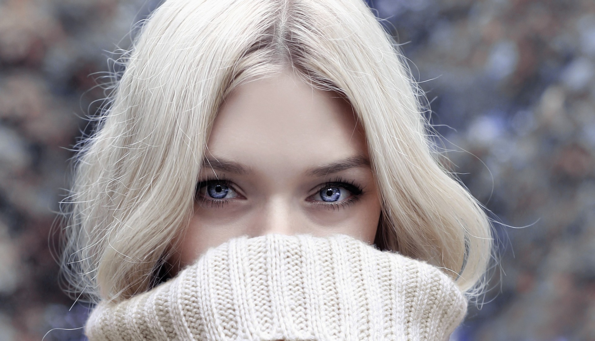 woman with sweater over her face and beautiful eyes looking over the top of it.